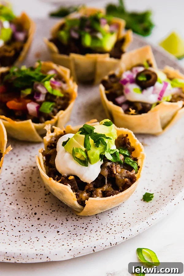 A neatly arranged plate showcasing several loaded mini taco cups, garnished with fresh toppings.