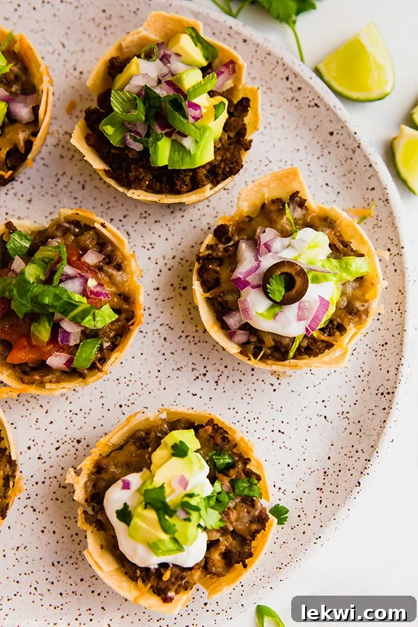 A close-up of a plate with several perfectly baked and topped mini taco cups.