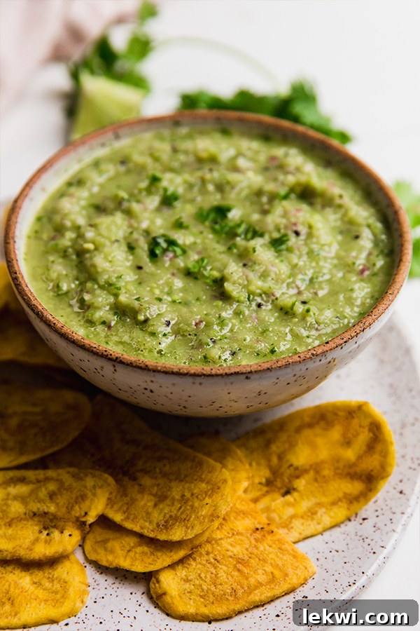 A bowl of vibrant Nightshade-Free Salsa Verde, surrounded by crispy plantain chips, ready for dipping.