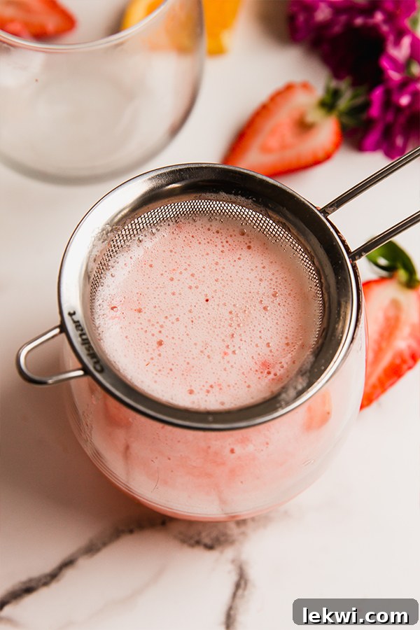 A cup of perfectly garnished strawberry mimosa mocktail, ready to be enjoyed.