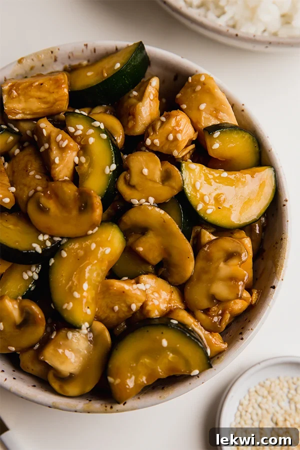 A bowl of homemade mushroom chicken stir fry, garnished with sesame seeds.