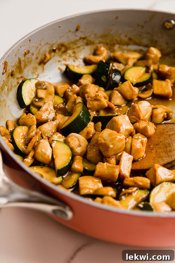 Mushroom chicken stir fry cooking in a large skillet, with vibrant vegetables and chicken pieces.