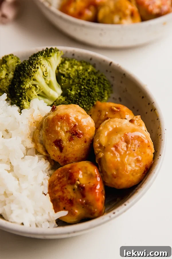 A bowl of freshly cooked orange chicken meatballs served with white rice and steamed broccoli, ready to enjoy.