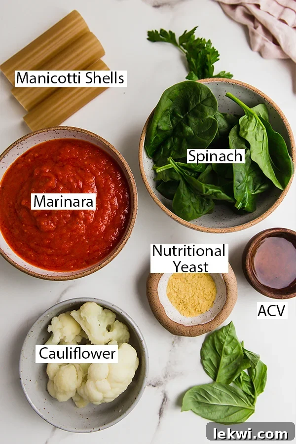 A vibrant flat lay of all the fresh ingredients for gluten-free cauliflower manicotti, including cauliflower florets, spinach, seasonings, and manicotti shells.