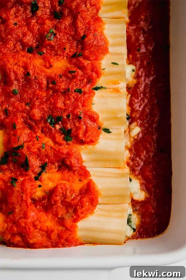 A large baking dish filled to the brim with perfectly baked gluten-free cauliflower manicotti, garnished with fresh herbs, ready to be served.
