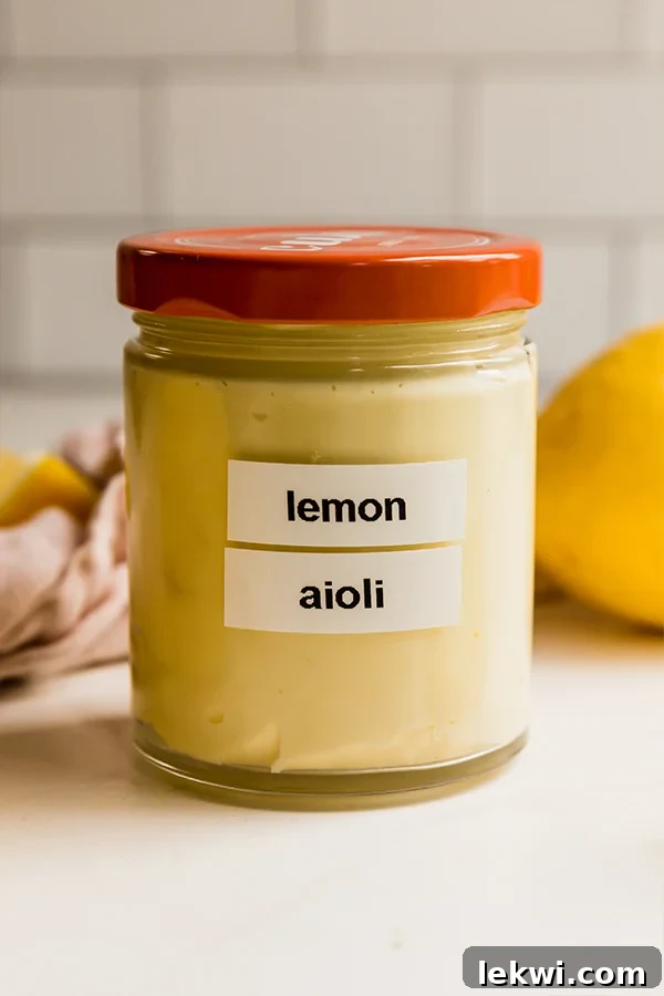 A glass jar with a red lid holds homemade lemon aioli, ready to serve.