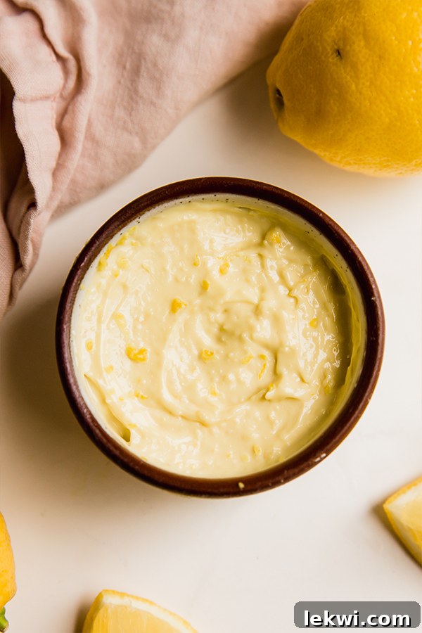 A beautifully presented bowl of creamy lemon aioli, garnished with fresh herbs.