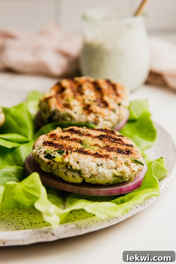 Avocado ranch chicken burgers on lettuce on a white plate, ready to eat.