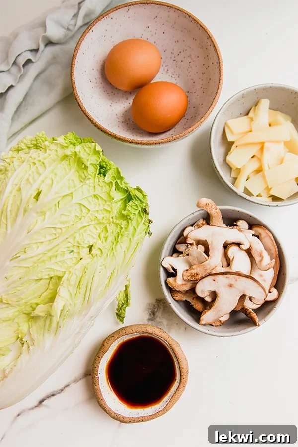 A vibrant display of fresh ingredients for homemade Moo Shu chicken, including chicken breast, napa cabbage, shiitake mushrooms, bamboo shoots, and a selection of sauce components arranged beautifully.