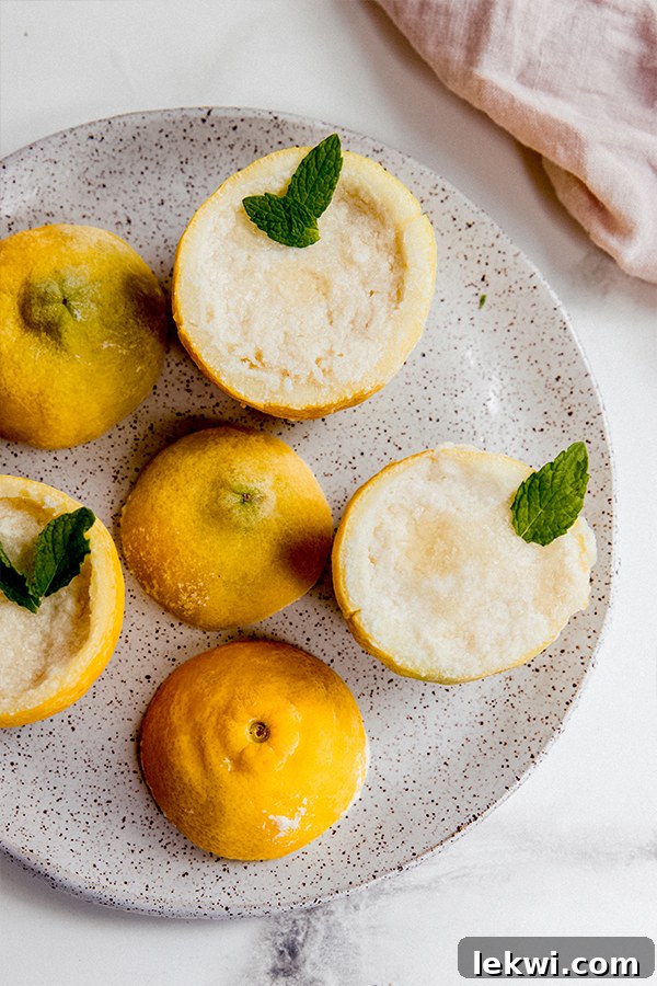 A beautifully arranged plate featuring several lemon sorbet cups, each nestled in a lemon rind and adorned with fresh mint leaves.