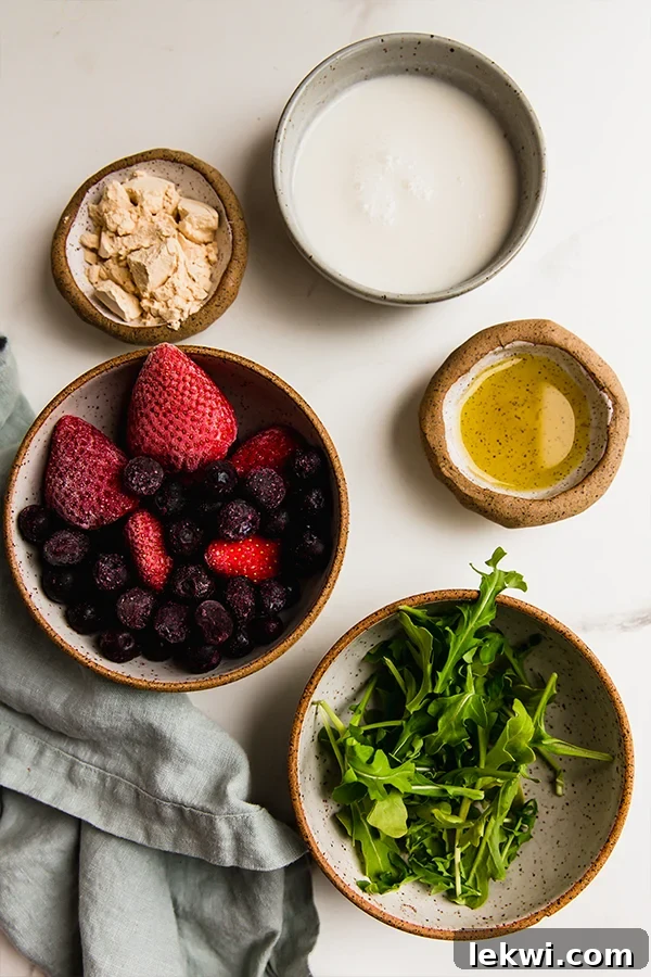 Ingredients including frozen wild blueberries, arugula, and protein powder laid out on a table.