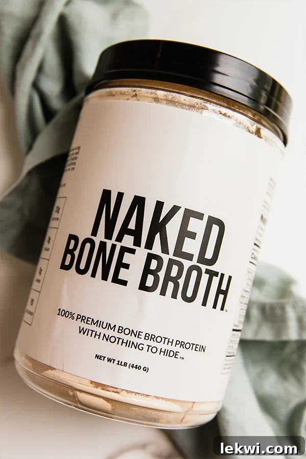 Container of Naked Bone Broth protein powder on a wooden surface.