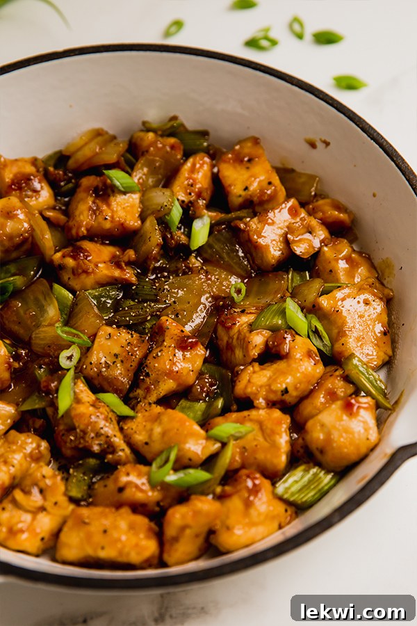 A perfectly plated bowl of Black Pepper Chicken stir-fry, garnished with fresh green onions and an extra sprinkle of black pepper, ready to be enjoyed.