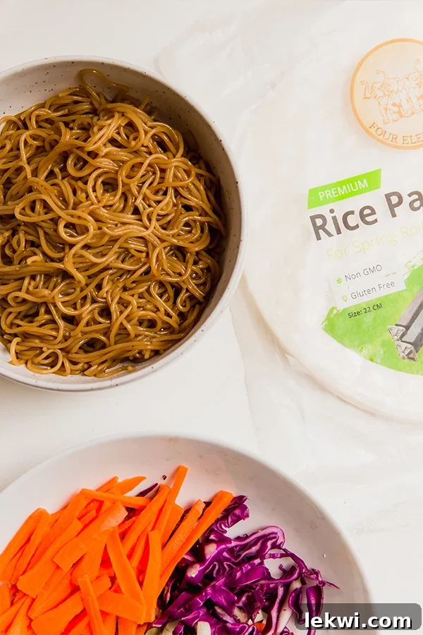 A selection of fresh ingredients laid out, including gluten-free ramen, rice paper, shredded cabbage, and carrots, ready for making crispy ramen rice paper rolls.