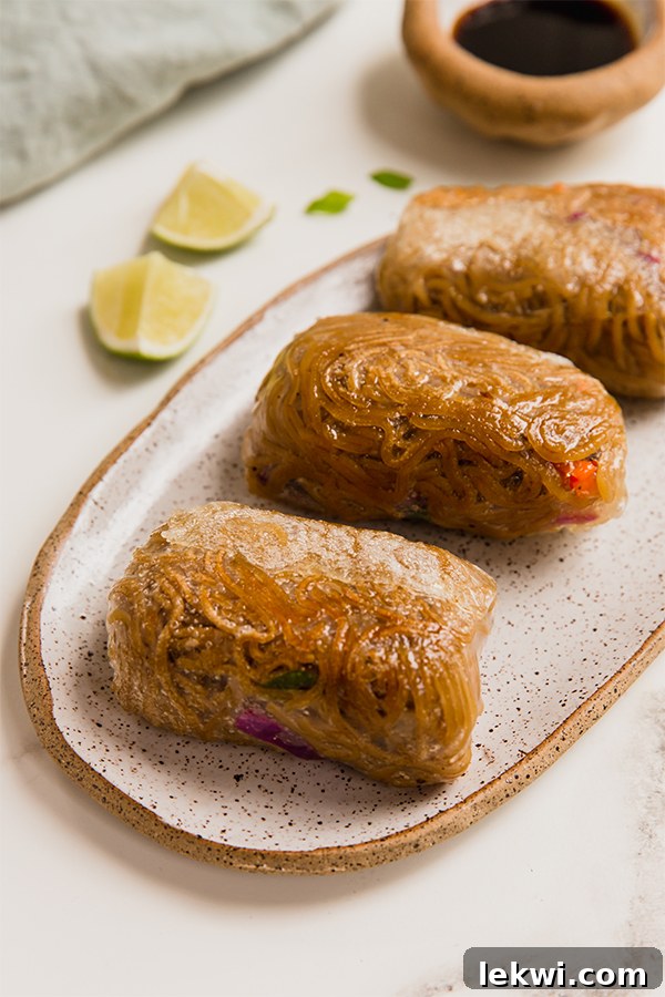 A plate generously filled with golden-brown, crispy ramen rice paper rolls, garnished with green onions and ready to be served.