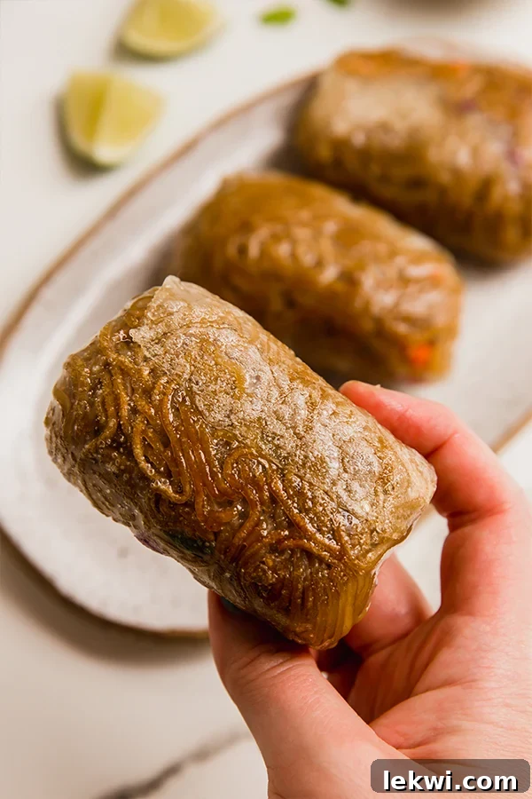 Person holding a crispy ramen rice paper roll over a platter.