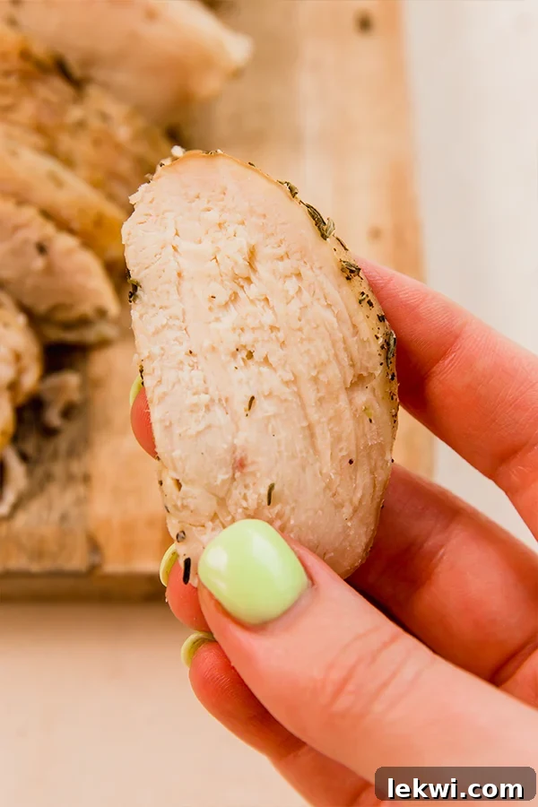 A perfectly thin slice of homemade chicken lunch meat, showcasing its tender texture and appealing color.