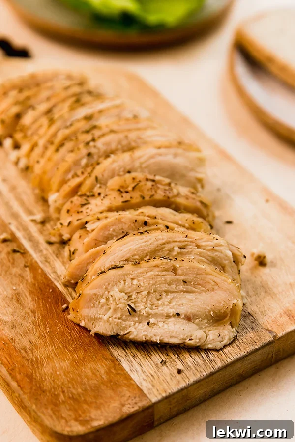Thinly sliced homemade chicken deli meat arranged artistically on a cutting board, emphasizing its uniform texture.