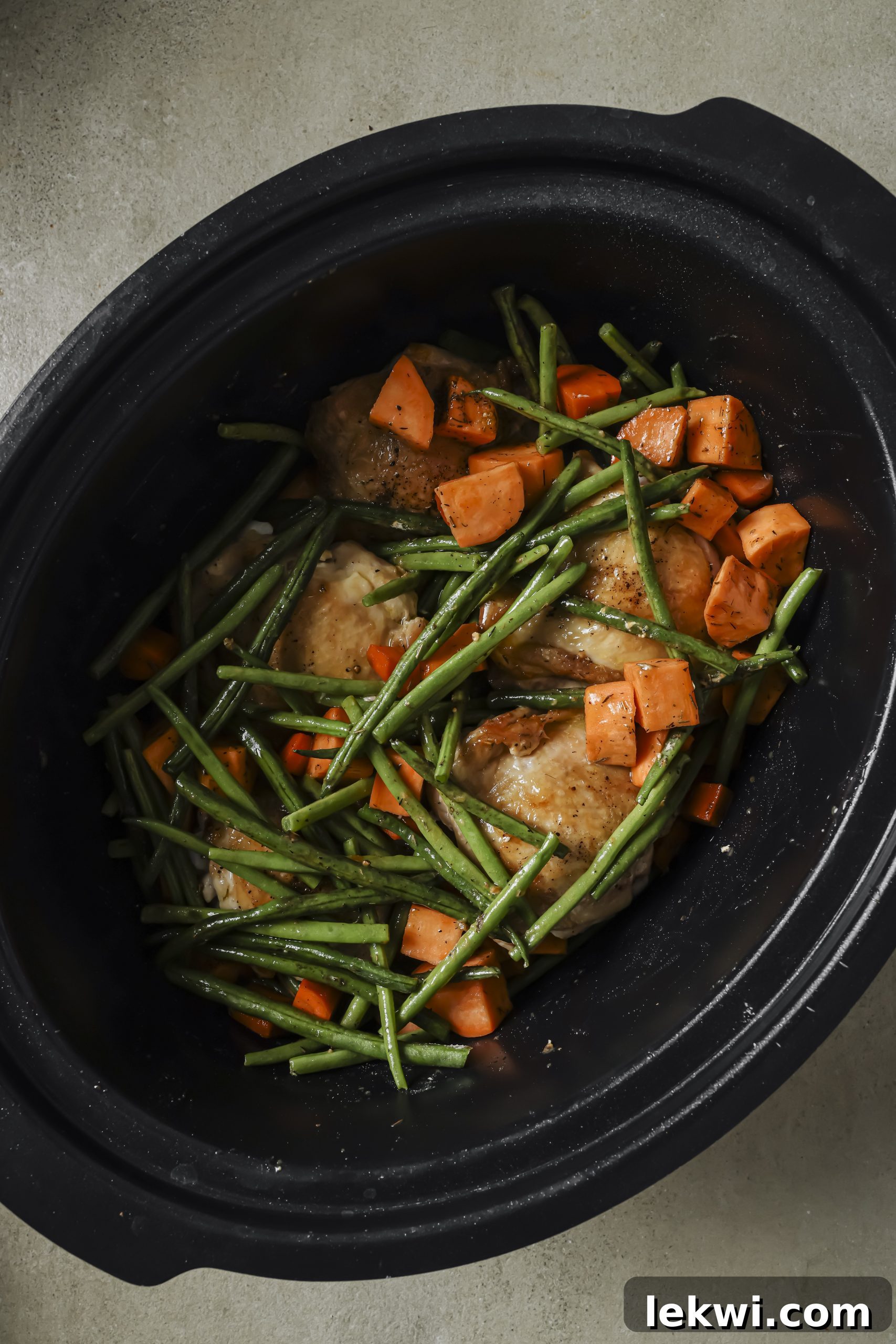 Chicken and vegetables layered in a slow cooker, drizzled with balsamic and broth.