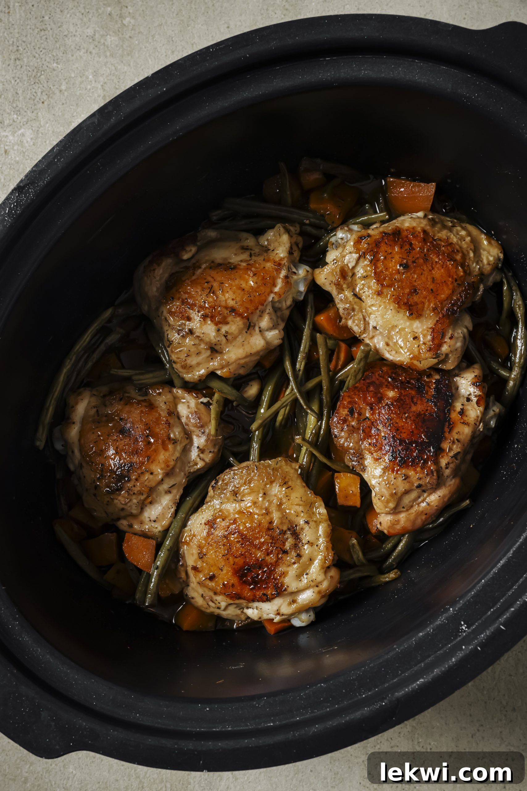 Lidded slow cooker with balsamic chicken and vegetables, gently cooking.