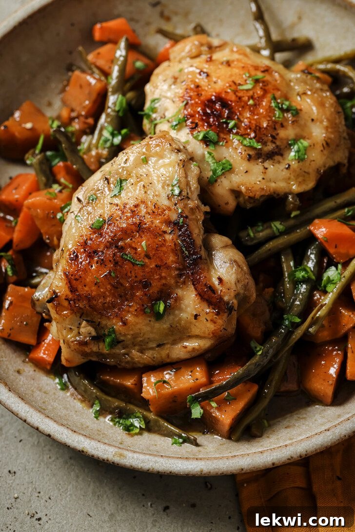 Close-up of Slow Cooker Balsamic Chicken served over tender vegetables, garnished with fresh parsley.