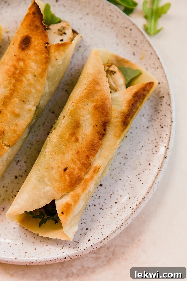 Two perfectly prepared gluten-free chicken pesto wraps, sliced in half and arranged appealingly on a white plate, ready to be served.
