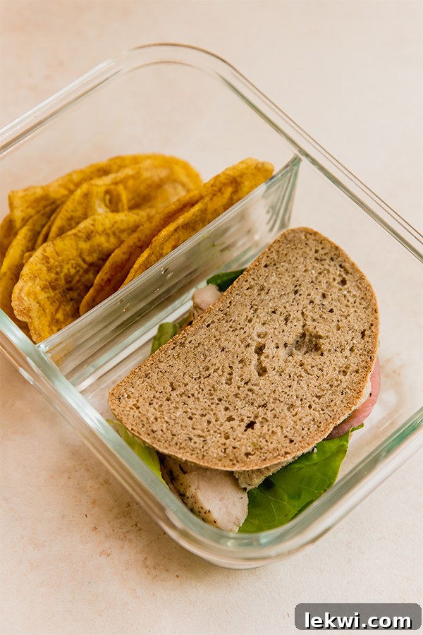 One adult lunchable container with a grain-free sandwich, plantain chips, and apple slices.