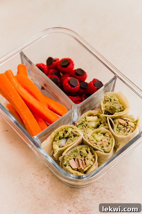 Avocado tuna pinwheel lunchable with raspberries, chocolate gems, and carrot sticks.