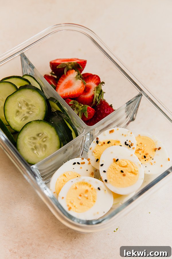 Everything Bagel Egg Lunchable featuring sliced hard-boiled eggs, cucumber, and strawberries.