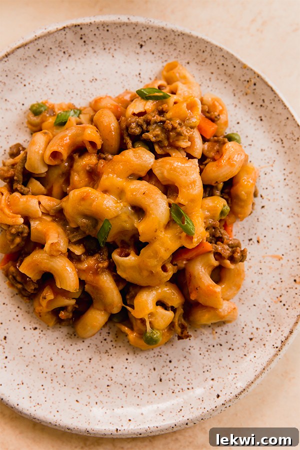 A portion of sloppy joe pasta casserole served on a white plate with a fork.