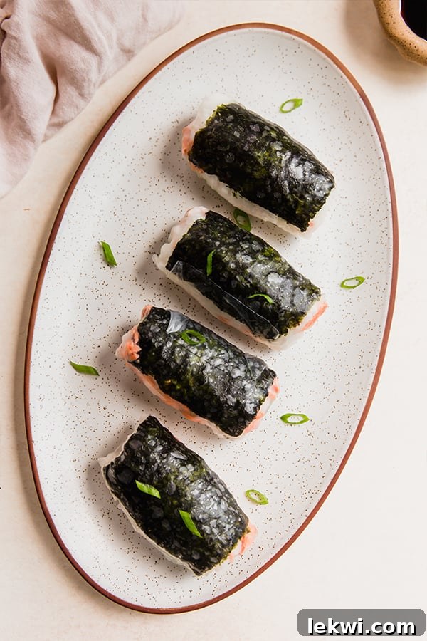 A plate with beautifully arranged sushi inspired salmon rice paper rolls on it.