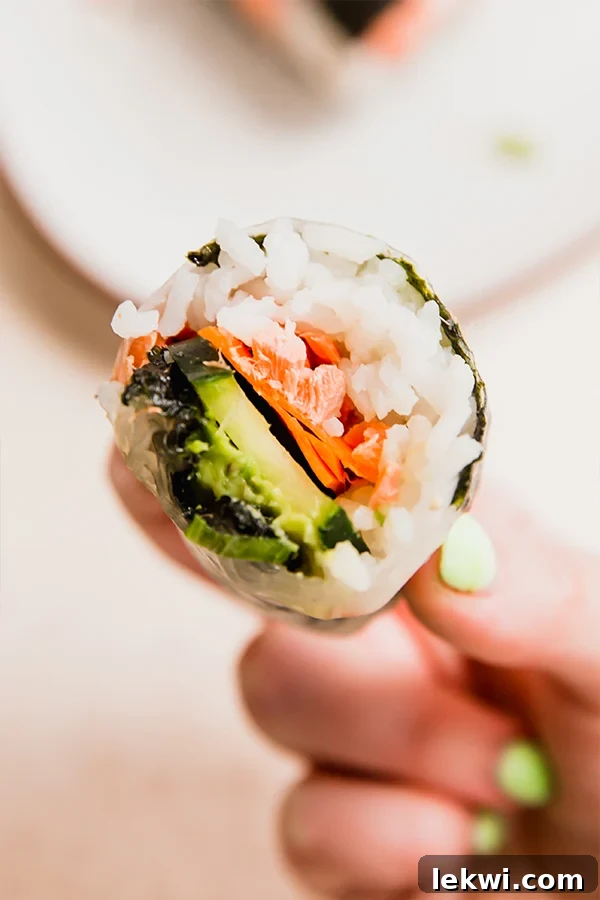 Person holding a salmon rice paper "sushi" roll.