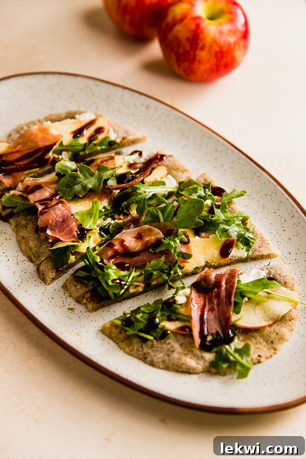 A fully prepared apple balsamic flatbread on a serving plate, garnished and ready to be enjoyed.