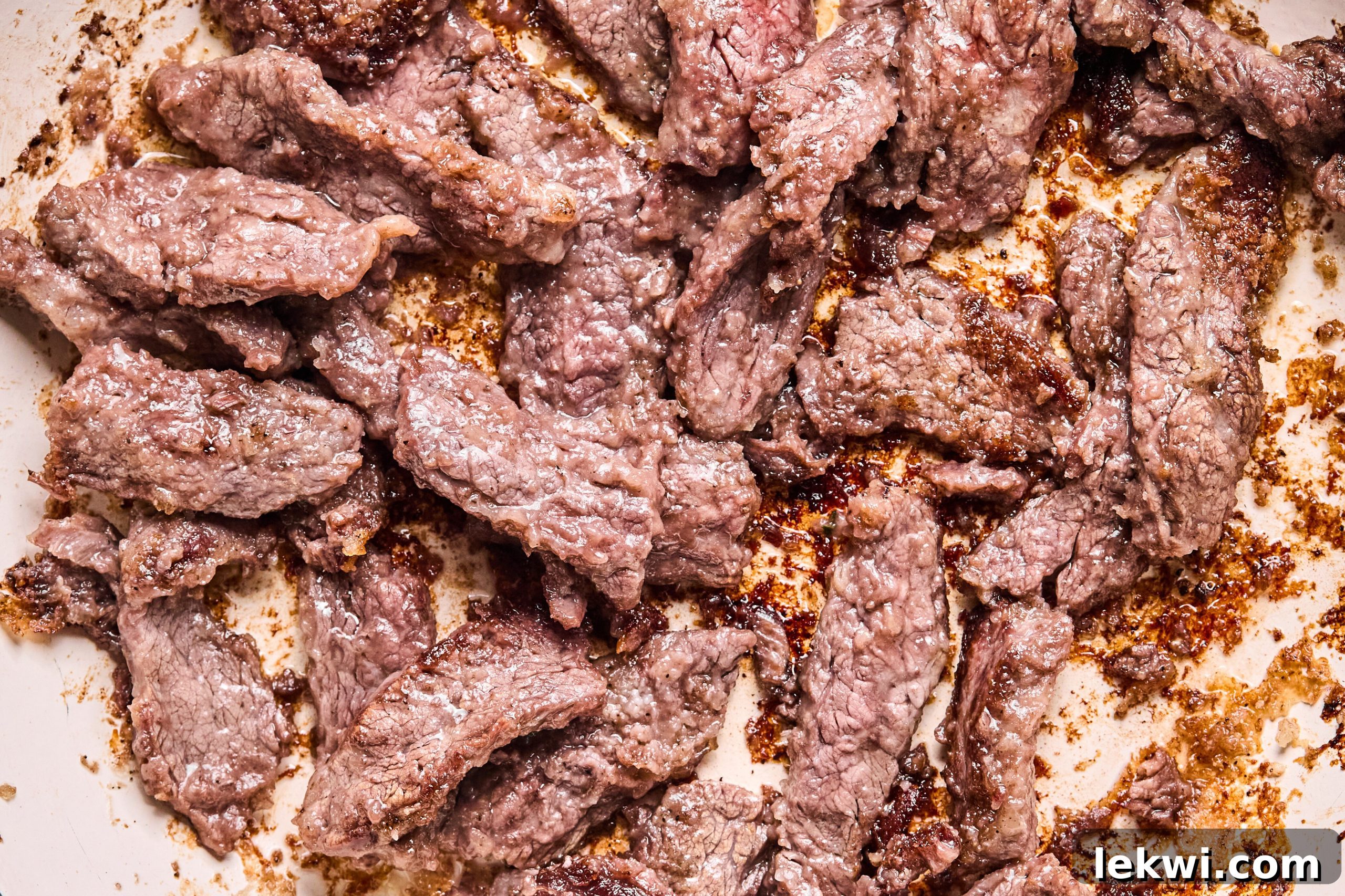 The flank steak sauting in a pan.