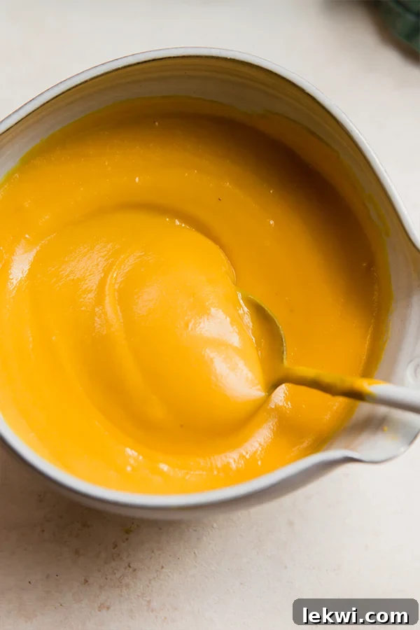 A spoon in a bowl of dairy-free cheese sauce.