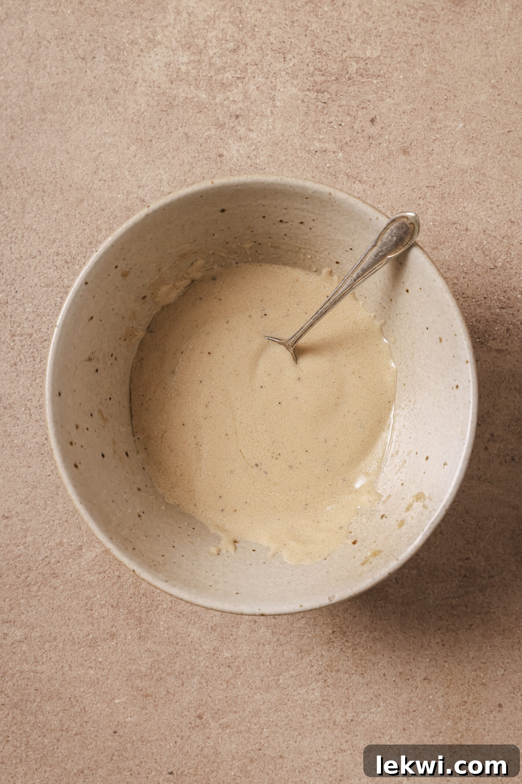 Harvest bowl dressing whisked in a bowl with a spoon.