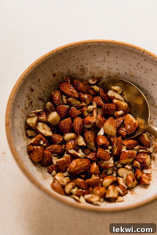 Close-up shot of chopped almonds mixed with coconut oil, coconut sugar, and cinnamon in a small bowl, ready for baking.