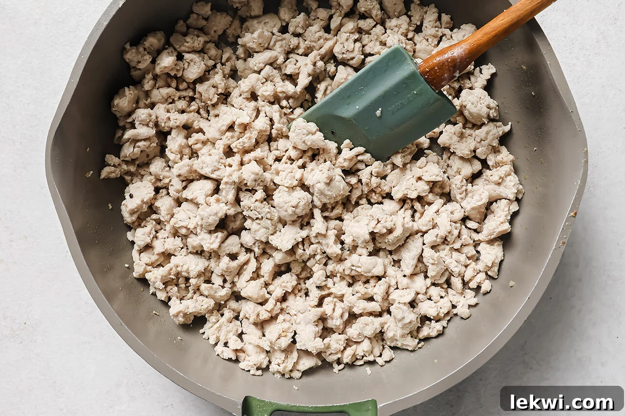 Ground chicken cooked, fully cooked and crumbled in a pan.