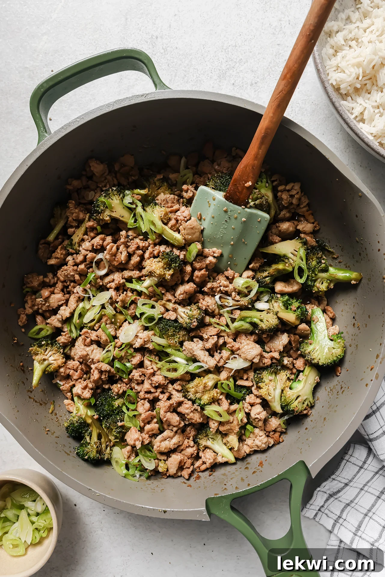 Ground chicken and broccoli fully cooked in a large green pan.