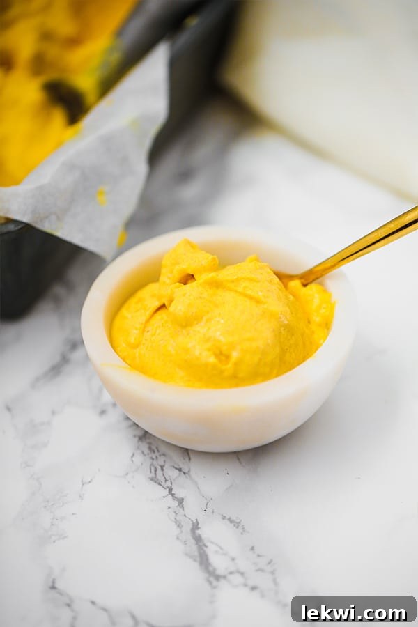 A bowl of luscious mango turmeric ice cream with a spoon ready for tasting.