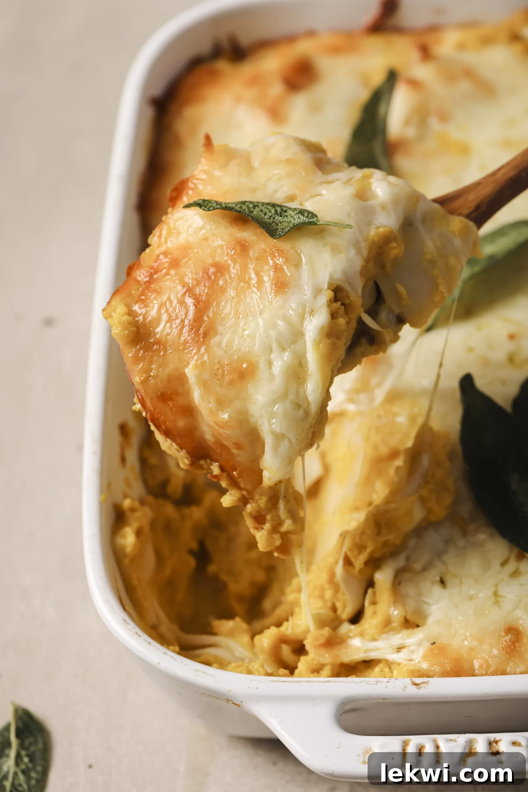 Butternut squash lasagna in a pan, with one roll up being pulled up with a spatula.