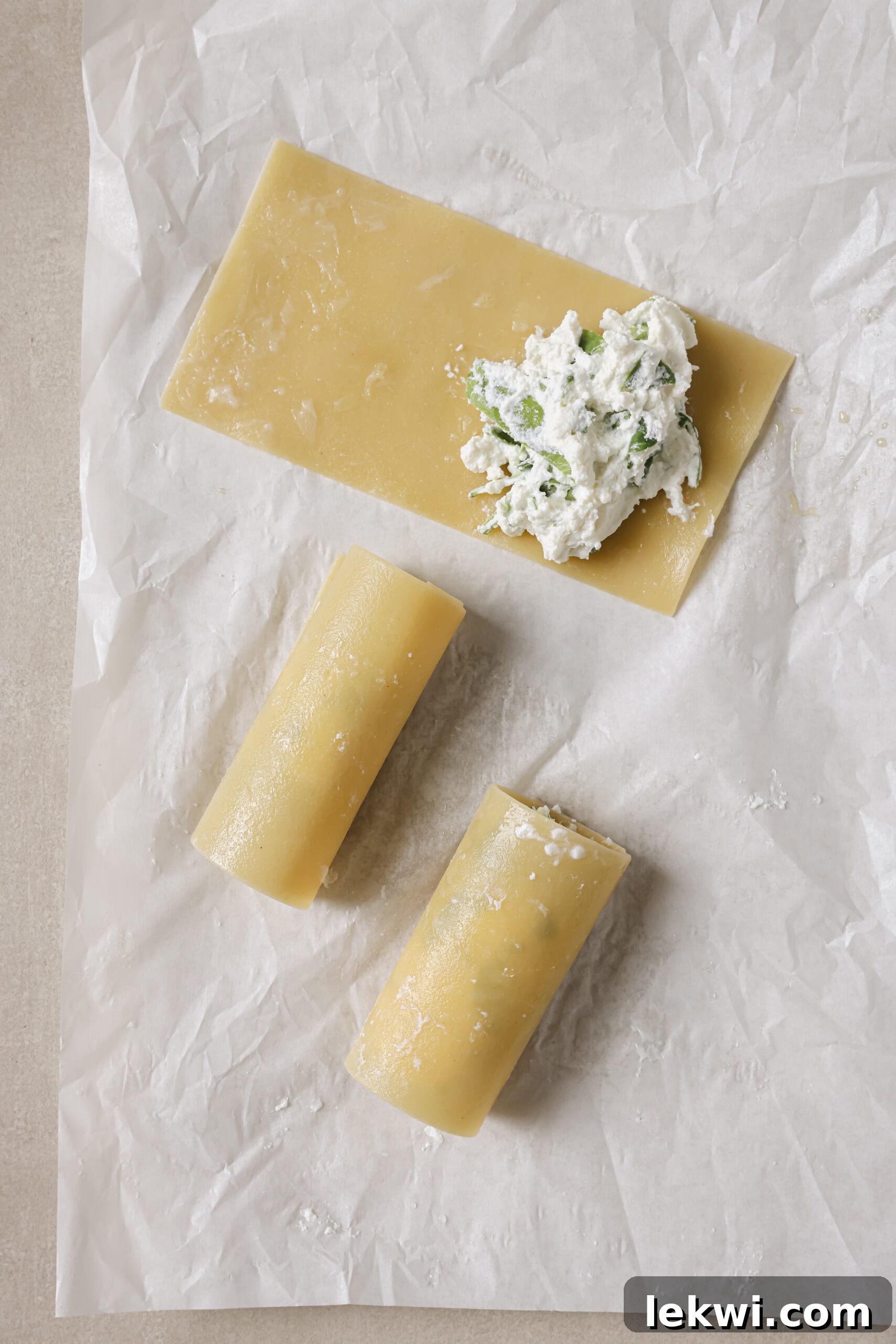 Lasagna sheet being rolled with ricotta filling.