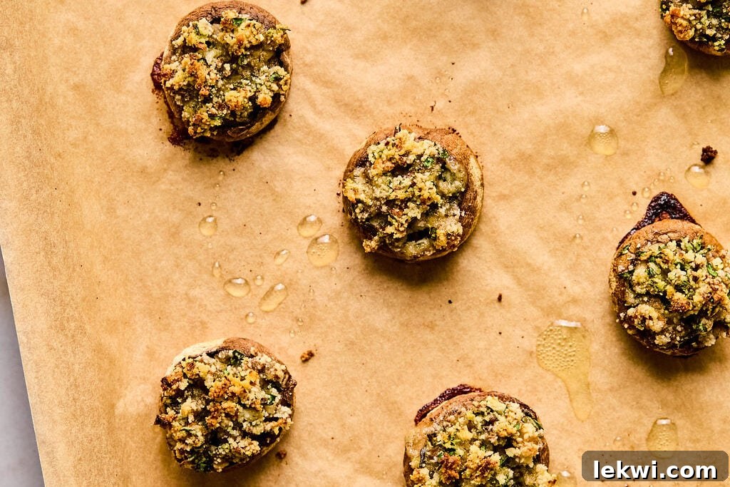 A baking sheet filled with perfectly baked stuffed mushroom caps, golden brown and tender, fresh out of the oven.