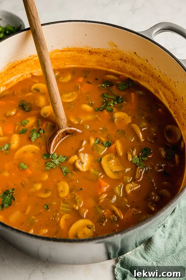 hungarian mushroom soup in a large stock pot with a wooden spoon.