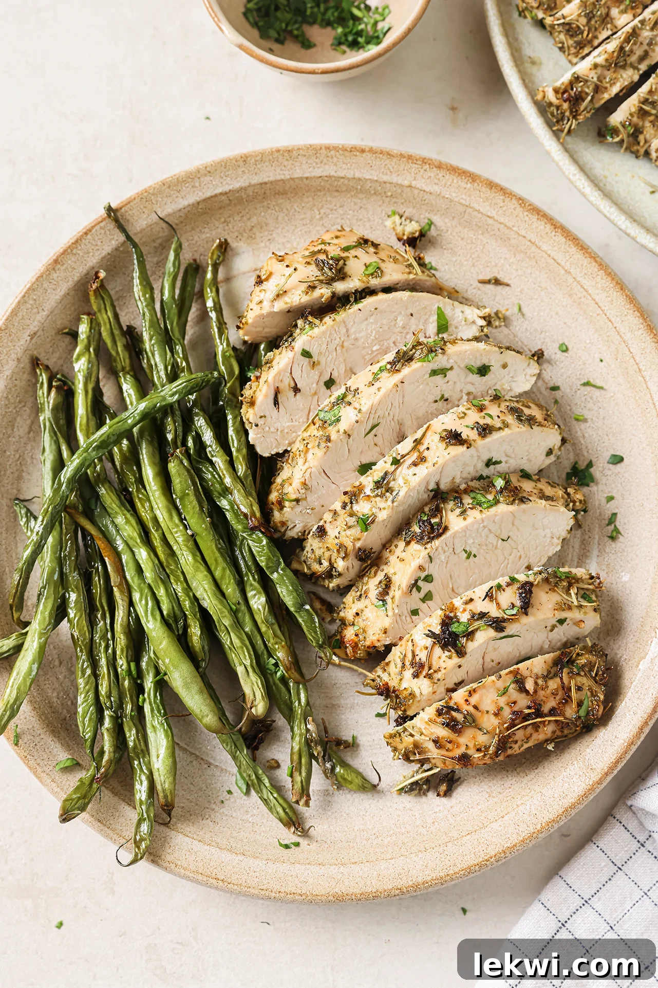 Turkey tenderloin sliced on a plate with green beans, showing the finished dish.