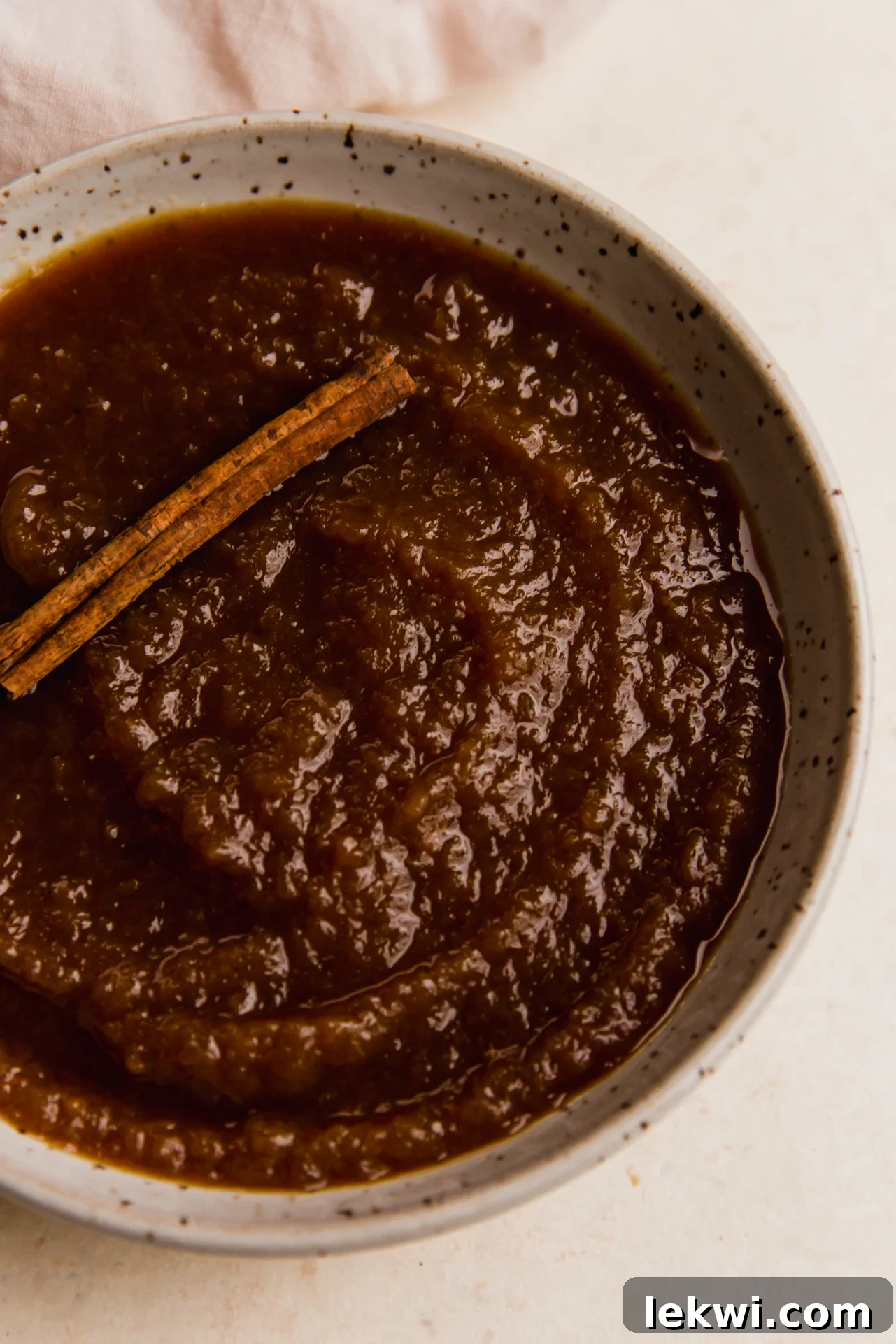 Slow cooker apple sauce topped with a cinnamon stick, showcasing its rich, homemade texture.