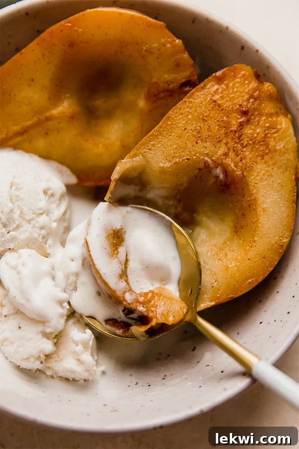 Spoon digging into a baked pear, showing its soft, caramelized interior.