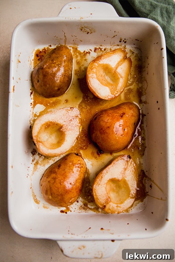 Baked pears, golden brown and tender, resting in a baking dish after being removed from the oven.