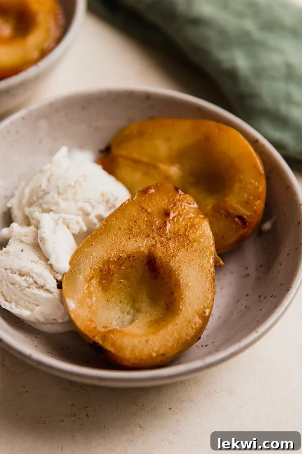 Two baked pear halves in a bowl with ice cream.