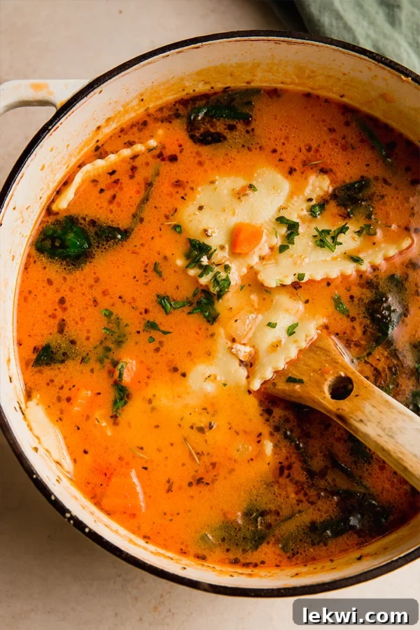 Ravioli soup in a large pot with a wooden spoon, ready to be served.